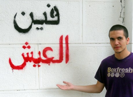 Eoghain Ellis beside a protest slogan in arabic which reads ‘Where is the bread?’ in reference to the announcement that the governement was to ration bread