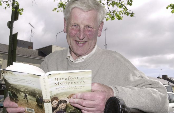 Bryan Gallagher looking over a copy of his book, Barefoot in Mullyneeny.