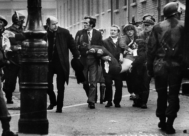 Bishop Daly helps clear a path for a man badly injured during Bloody Sunday in Derry
